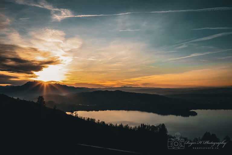 Sonnenuntergang über dem Zugersee mit Sonnenstrahlen über dem Pilatus